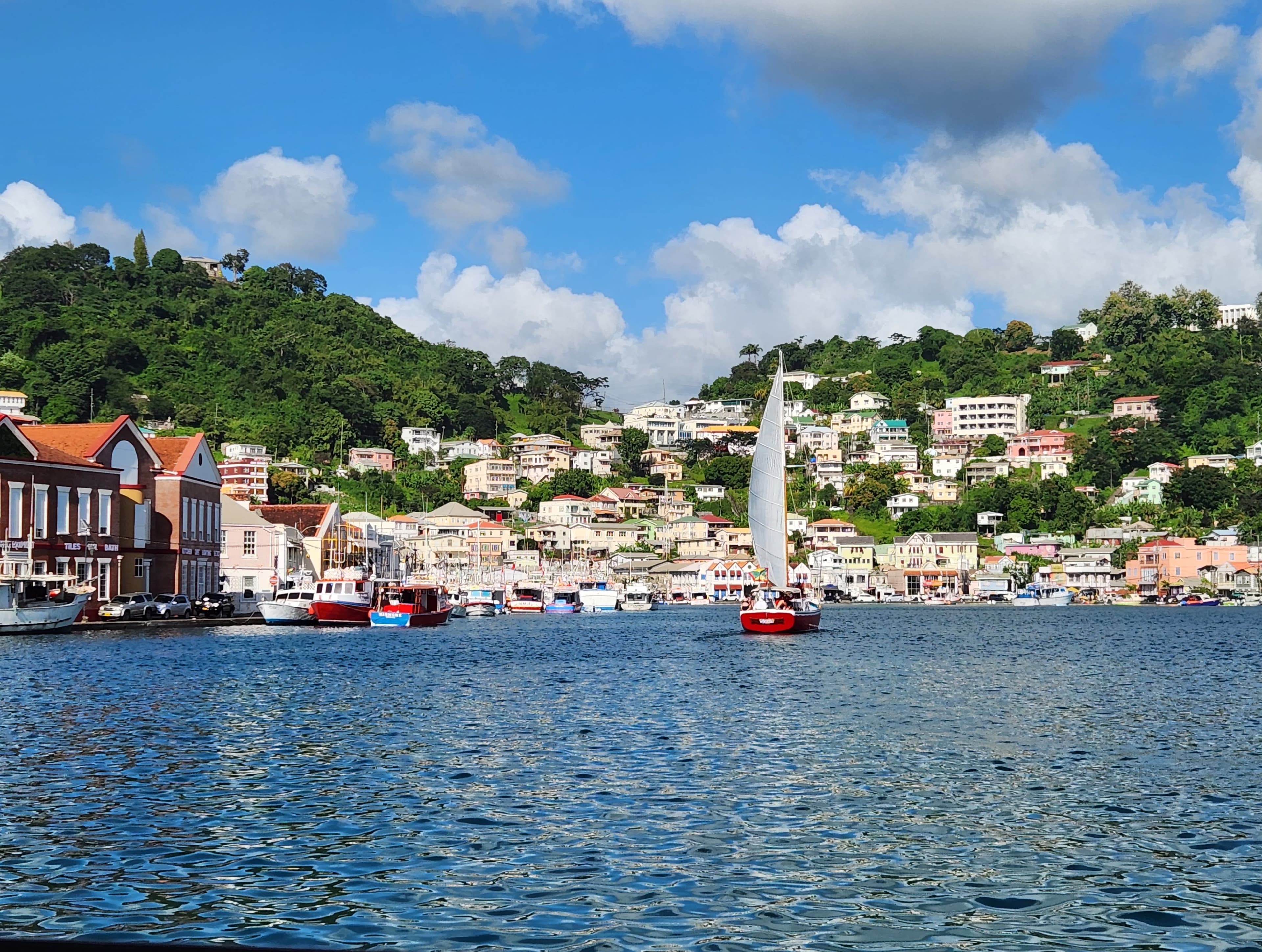 Harbor view with sailboats and colorful hillside buildings.
