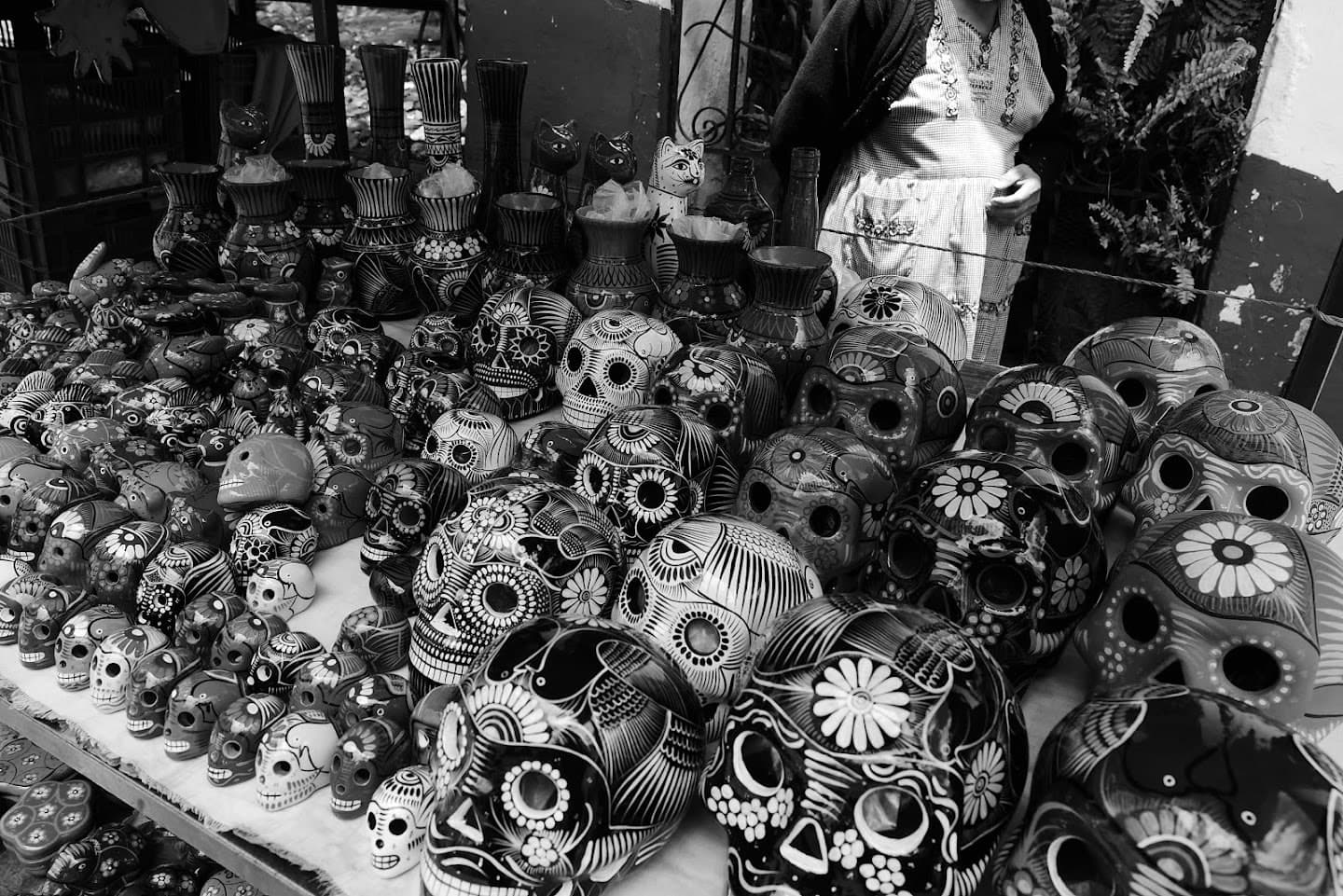 Painted decorative skulls and ceramic vessels arranged across a crowded table.