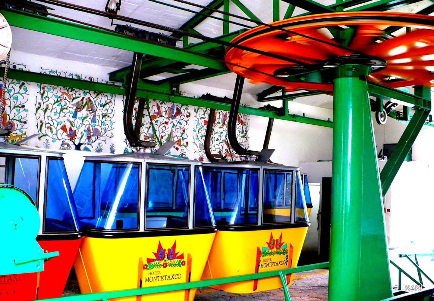 Yellow gondola cabins beneath red and green cable-car machinery.